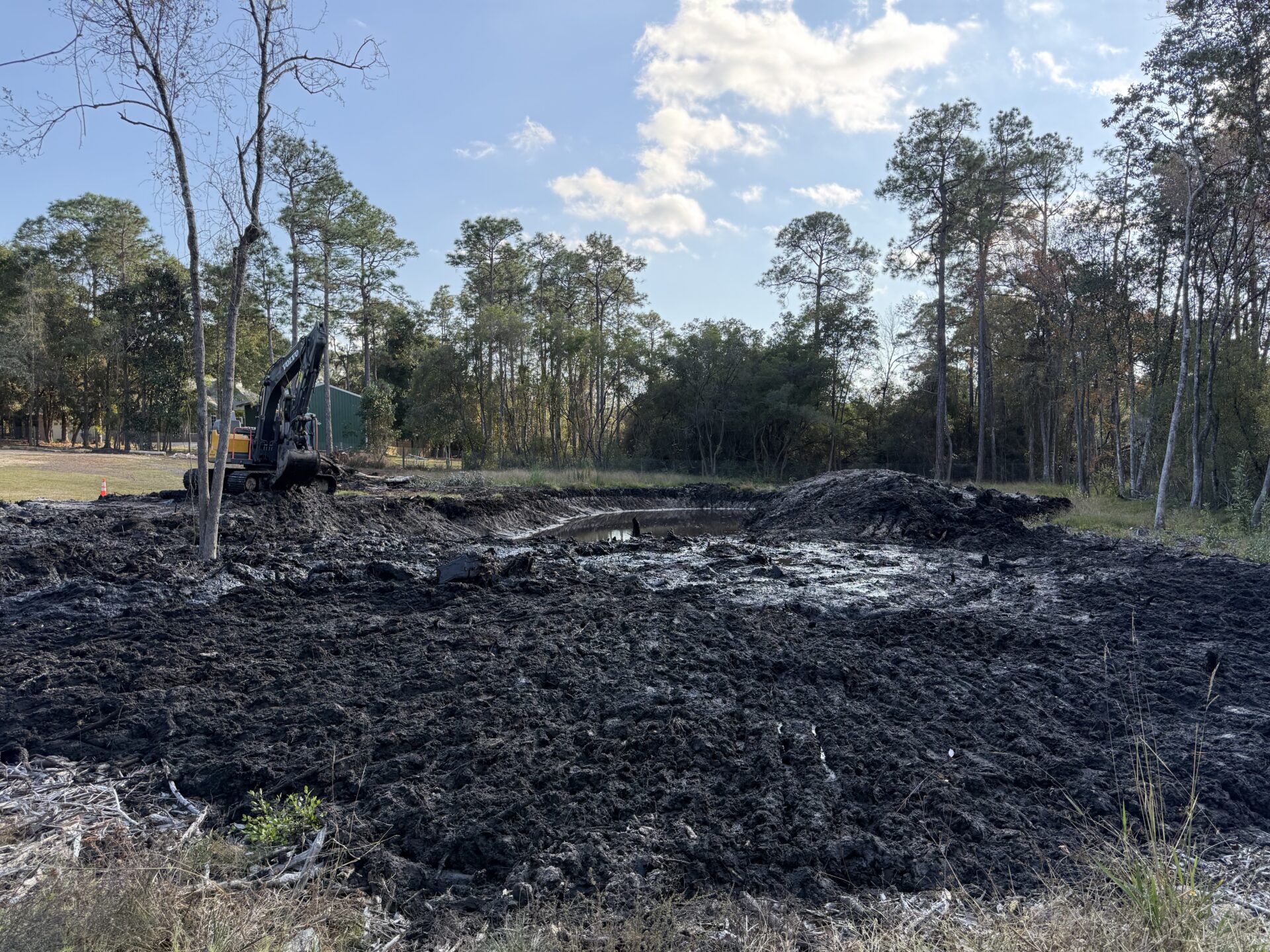 Large-scale pond excavation showing mud removal and reshaping of the basin in Pensacola, Florida.